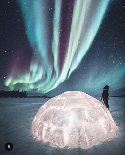 Viendo la aurora boreal a lado de un iglú