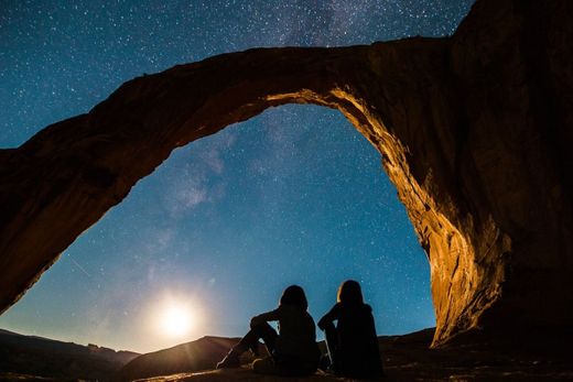 two person sitting under rock monolith photo – Free Image - Unsplash