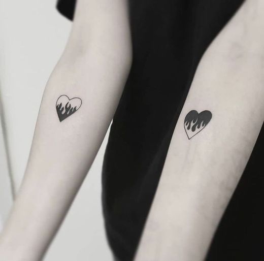 Tatuagem duplinha de corações pegando fogo.